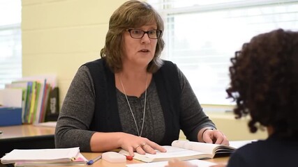 Teacher Helping Student at Desk