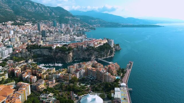 Luxury drone panorama of Monaco&rsquo;s dramatic cliff‑top Old Town, super‑yacht harbours of Port Hercule and Fontvieille, terracotta apartments and sparkling Mediterranean framed by Alpine foothills.