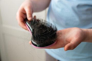 Girl hands clean the comb from fallen hair. Close up. White background. Concept of hair loss,...
