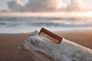 Serene beach scene featuring a wooden comb resting on driftwood. Evokes feelings of nature, selfcare, and mindful simplicity. Ideal for beauty, wellness or travel related content.