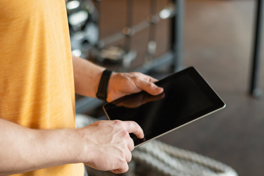 Personal trainer or sporty man holding tablet at gym or fitness center. Check workout plan. Trainer making exercise plan.