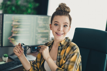 Young female programmer in casual attire sitting at workplace with computers in the background...