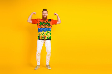 Young man with beard in colorful tropical shirt posing confidently on vibrant yellow background,...