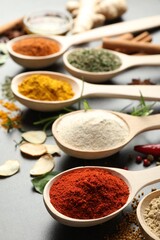 Many different spices in spoons on grey table, closeup