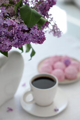 Bouquet of beautiful lilac flowers, coffee and dessert on white table indoors