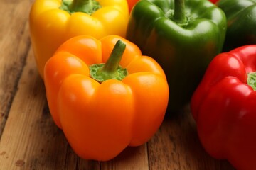 Fresh colorful bell peppers on wooden table, closeup