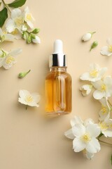 Essential oil and beautiful jasmine flowers on beige background, flat lay