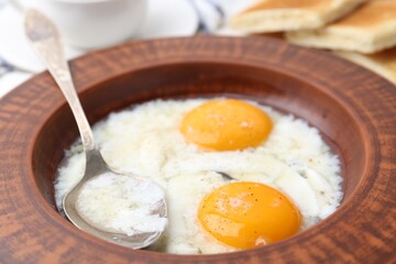 Half-boiled eggs in plate and spoon on table, closeup. Traditional asian breakfast