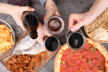 Friends with beer and snacks at grey table, top view