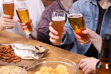 Friends with beer and snacks at wooden table, closeup