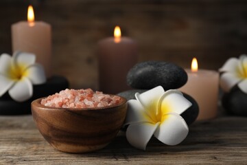 Composition with sea salt and spa stones on wooden table, closeup