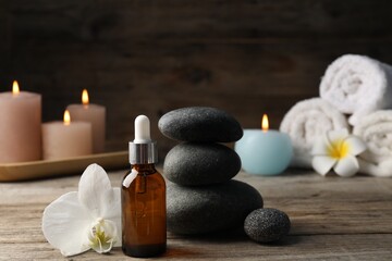 Composition with cosmetic product and spa stones on wooden table, closeup