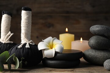 Composition with herbal bags and spa stones on wooden table, closeup