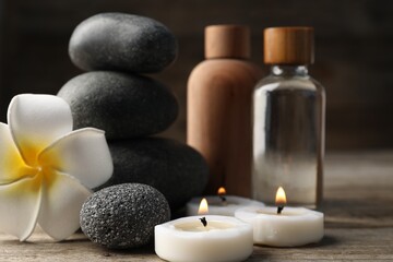 Composition with cosmetic products and spa stones on wooden table, closeup
