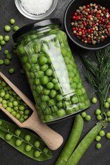 Fresh green peas in pickling jar, pods, spices and salt on black table, flat lay