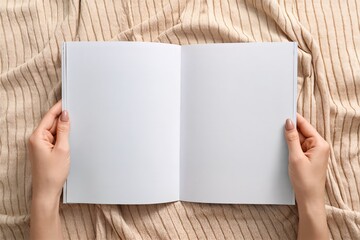 Obraz premium A beautifully serene view of an open blank notebook carefully held on a soft, textured fabric surface