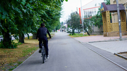 Bicyclist rides along a tree-lined street in a quiet neighborhood during late afternoon hours