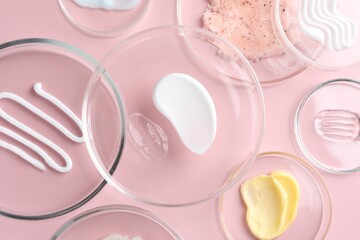 Different cosmetic products in Petri dishes on pink background, flat lay