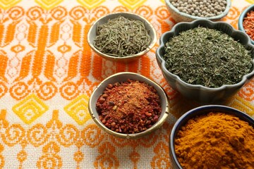 Many different aromatic spices in bowls on table with cloth, closeup. Space for text