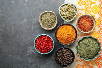 Many different aromatic spices in bowls on grey table with cloth, flat lay. Space for text