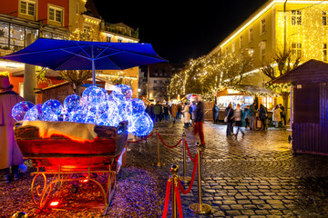 Atmospheric Christmas lights and market stalls in old town of Lindau with visitors at night. Bodensee, Germany