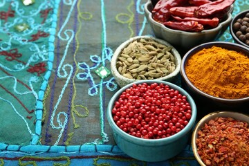 Many different aromatic spices in bowls on table with cloth, closeup. Space for text