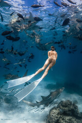 Woman free diver underwater in a tropical water with nurse sharks