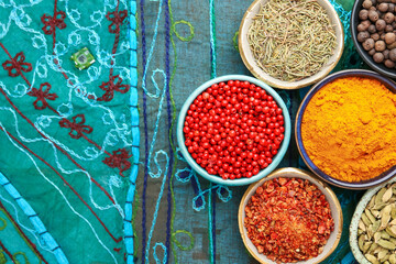 Many different aromatic spices in bowls on table with cloth, flat lay. Space for text