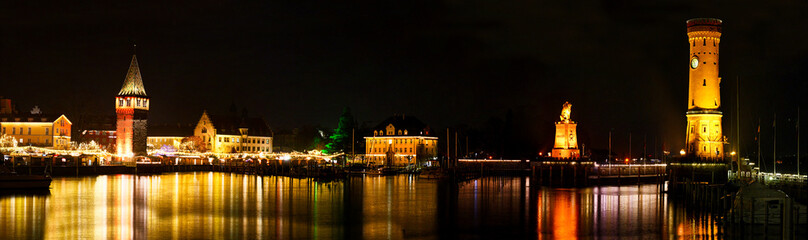 Obraz premium Panorama of Lindau harbor at night with Christmas lights, Mangturm, lion statue and lighthouse