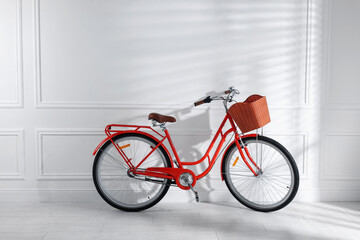 Fototapeta premium Red bicycle with basket near white wall indoors