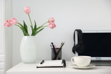 Desk with modern laptop, coffee and stationery in home office