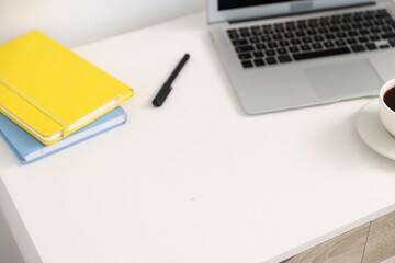 Desk with modern laptop, coffee and stationery in home office, closeup