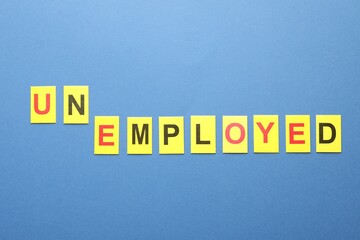 Word Unemployed on blue background, top view