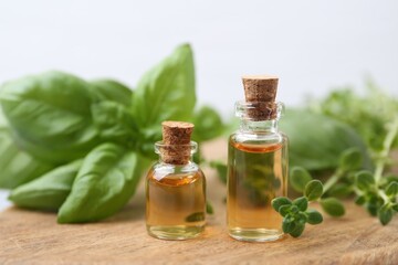 Bottles of essential oil and herbs on table, closeup