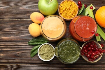 Superfood. Tasty smoothies in glasses and ingredients on wooden table, flat lay. Space for text
