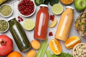 Superfood. Tasty smoothies in glass bottles and ingredients on light grey table, flat lay