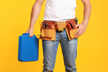 Professional repairman with tool box on orange background, closeup