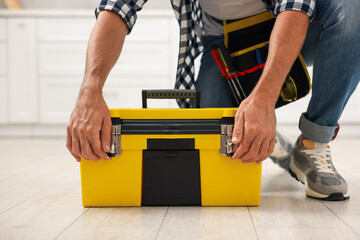 Professional repairman with tool box indoors, closeup