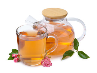 Aromatic tea in glass cup, teapot, roses and green leaves isolated on white