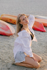 Blonde girl in a white shirt in the sea on the beach in the summer at sunset