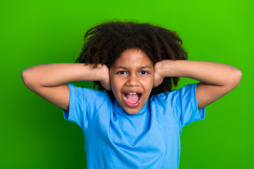 Excited young girl in vibrant mood posing with dramatic gesture against a vivid green background...