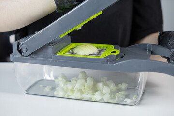 Modern gray and green vegetable chopper dicing an onion into small pieces, symbolizing efficient...