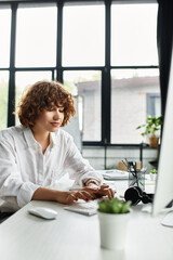 Young businesswoman with curly hair immersed in work at a modern office desk