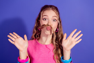 Playful young woman with long blonde hair making funny expressions against a vibrant purple...