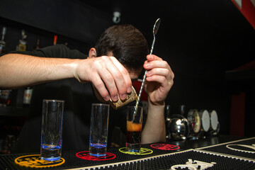 The bartender carefully and accurately makes a delicious shot on the bar counter	
