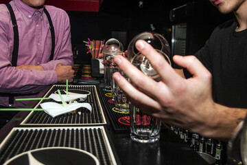 A bartender twirls a cognac shaker on a large glass while making a cocktail in front of guests	
