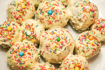 Round homemade cupcakes are sprinkled with all sorts of different decorations and beads and everything is stacked tightly on one round plate