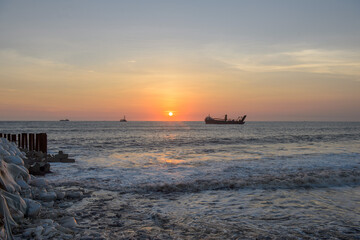 Sunset Over Ocean with Ships,The warm orange and purple hues of the sunset reflect beautifully on the sea surface, creating a peaceful maritime scene.