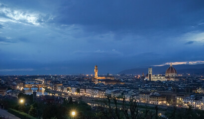 Panoramic evening view of the city of Florence in Italy from Piazzale Michelangelo and The sky is bright blue and the city is illuminated by lanterns.