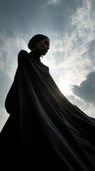 Silhouette of Woman in Flowing Cape Against Dramatic Sky